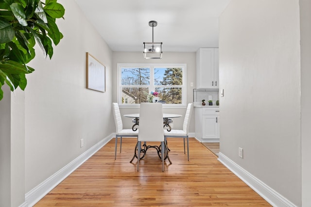 dining area with baseboards and light wood finished floors