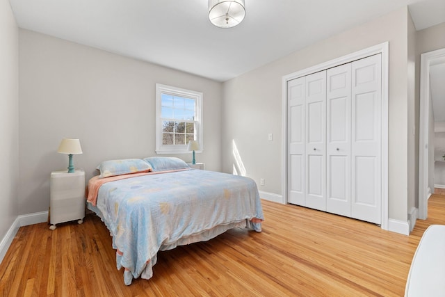 bedroom featuring light wood-style floors, baseboards, and a closet