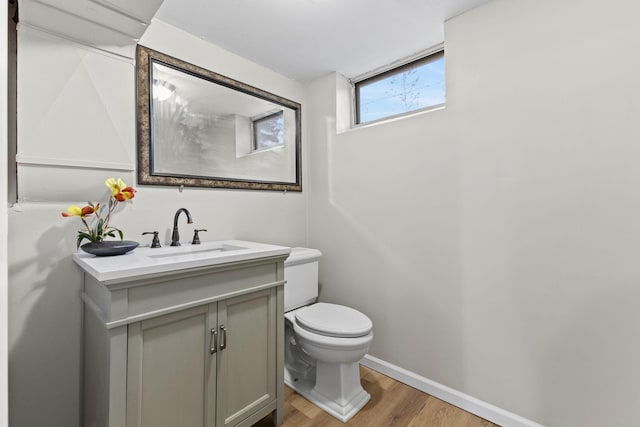 bathroom featuring toilet, vanity, baseboards, and wood finished floors