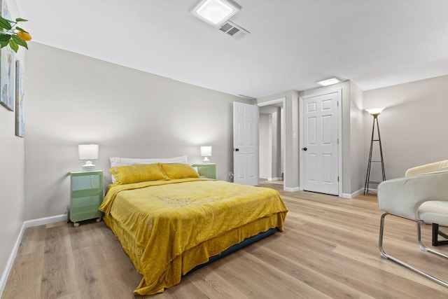 bedroom with visible vents, baseboards, and wood finished floors