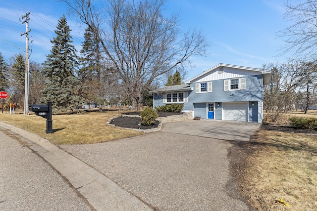 split level home with aphalt driveway, an attached garage, and a front lawn