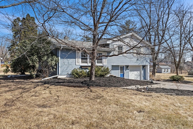 tri-level home featuring concrete driveway, an attached garage, and a front lawn