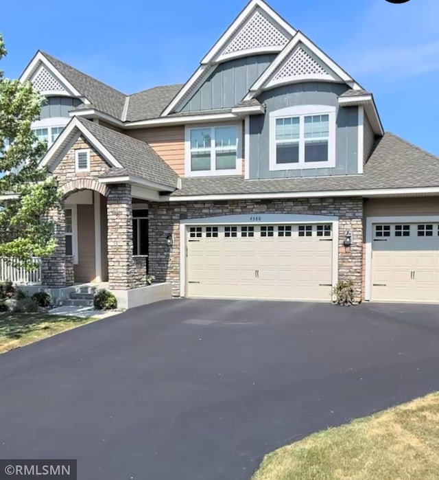 view of front of home with board and batten siding, aphalt driveway, and stone siding