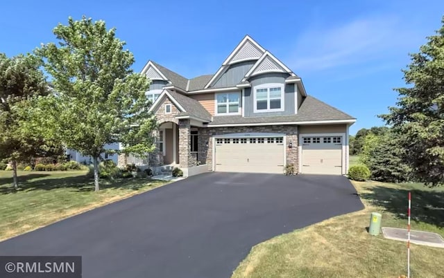 view of front of home featuring aphalt driveway, stone siding, an attached garage, and a front yard