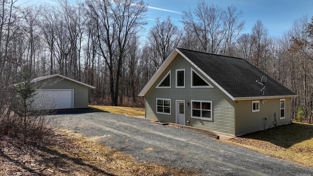 view of front of house with a garage, a shingled roof, and an outdoor structure