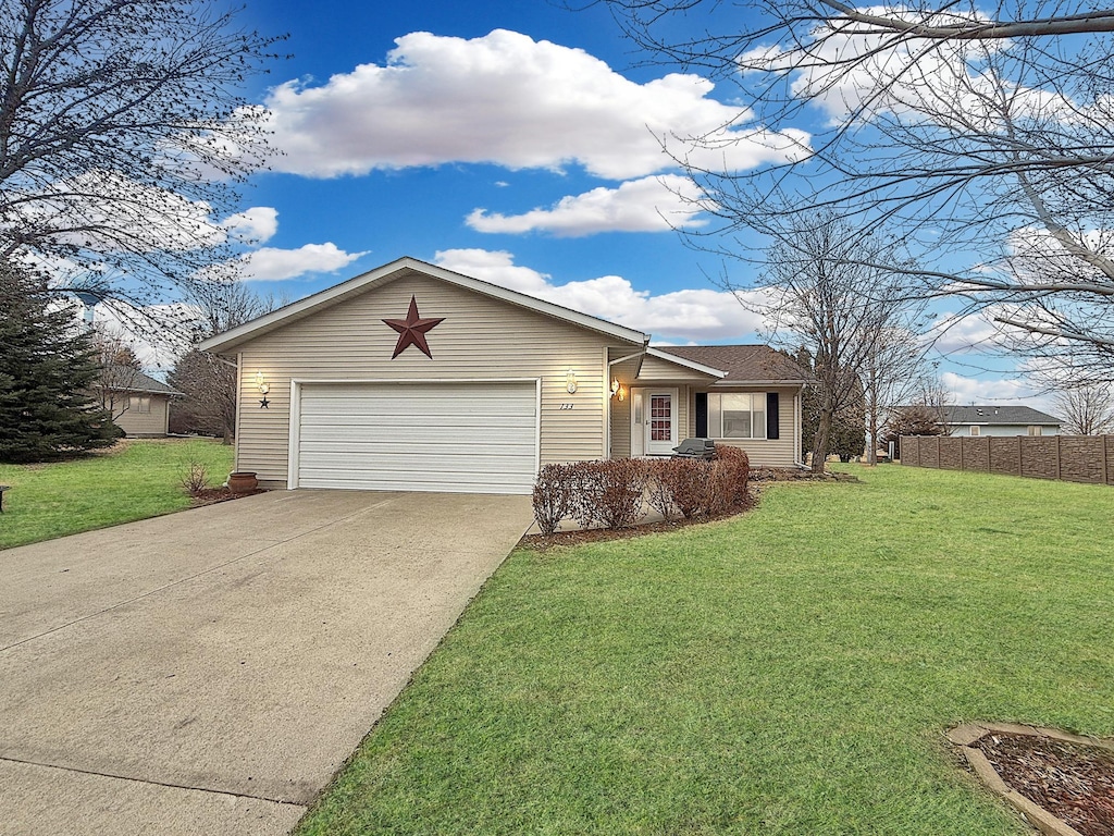 ranch-style home with a garage, concrete driveway, a front lawn, and fence