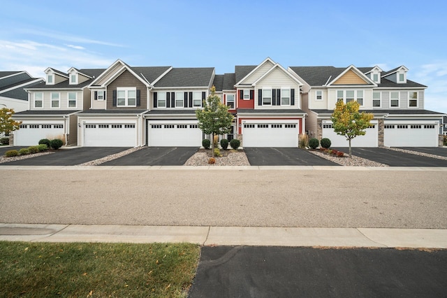 townhome / multi-family property featuring aphalt driveway, a residential view, and an attached garage