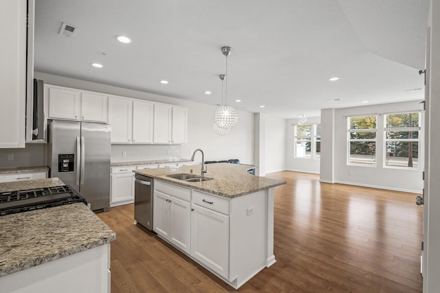 kitchen featuring a sink, tasteful backsplash, wood finished floors, white cabinetry, and stainless steel appliances