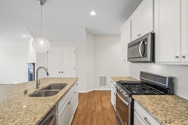 kitchen with visible vents, a sink, light wood-style floors, appliances with stainless steel finishes, and backsplash