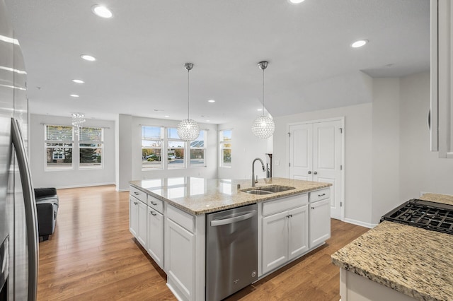 kitchen with a kitchen island with sink, light wood-style flooring, stainless steel appliances, and a sink