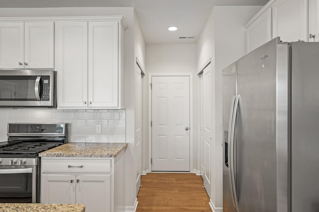 kitchen with white cabinetry, decorative backsplash, visible vents, and appliances with stainless steel finishes