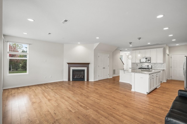 kitchen featuring visible vents, open floor plan, light wood-type flooring, appliances with stainless steel finishes, and white cabinets