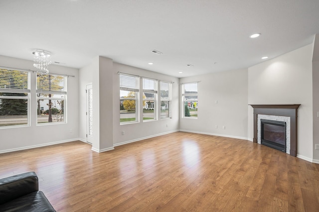 unfurnished living room with light wood-style flooring, baseboards, visible vents, and a chandelier