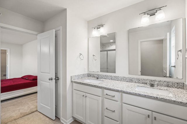 bathroom with a sink, an enclosed shower, double vanity, and tile patterned flooring