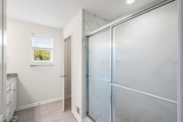 bathroom featuring vanity, tile patterned floors, baseboards, and a stall shower