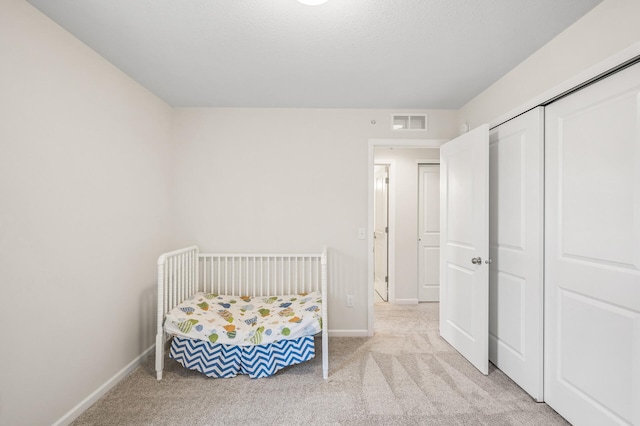 carpeted bedroom with visible vents, baseboards, and a closet