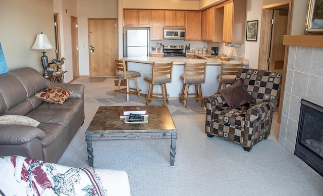 living area featuring light carpet and a tile fireplace
