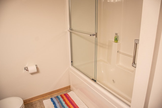 full bath featuring combined bath / shower with glass door, toilet, and baseboards