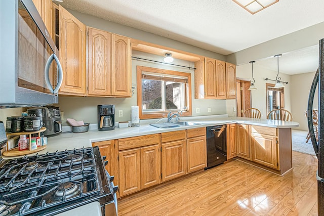 kitchen featuring a peninsula, a sink, light countertops, dishwasher, and stainless steel microwave