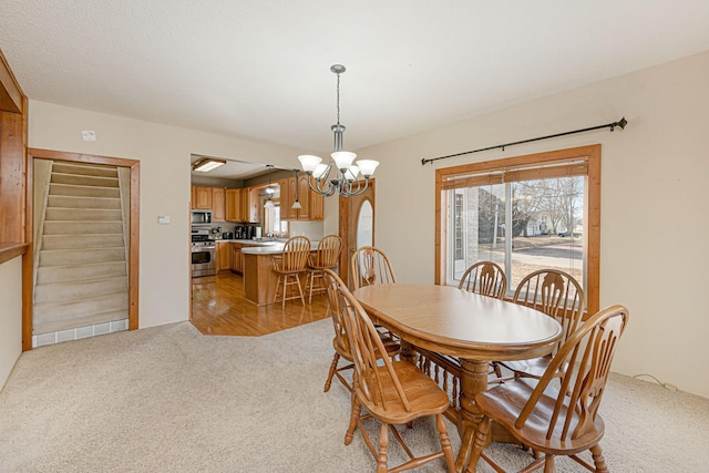 dining space featuring plenty of natural light, light colored carpet, stairway, and an inviting chandelier