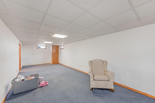 living area with a drop ceiling, carpet floors, and baseboards