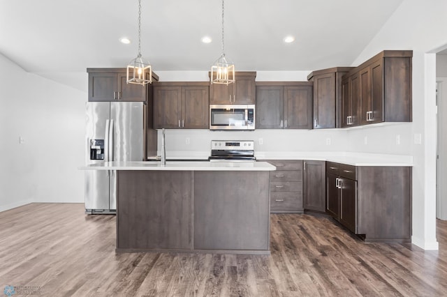kitchen with a kitchen island with sink, stainless steel appliances, light countertops, dark wood-type flooring, and dark brown cabinets