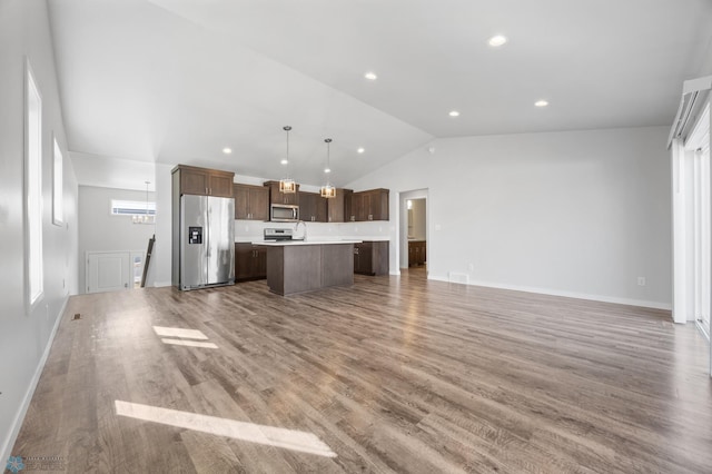 kitchen with a kitchen island, open floor plan, light wood-style floors, appliances with stainless steel finishes, and light countertops