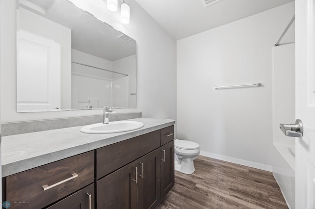 bathroom with vanity, wood finished floors, baseboards, toilet, and shower / bathtub combination