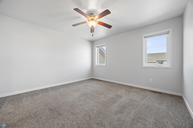 carpeted spare room with visible vents, baseboards, and a ceiling fan