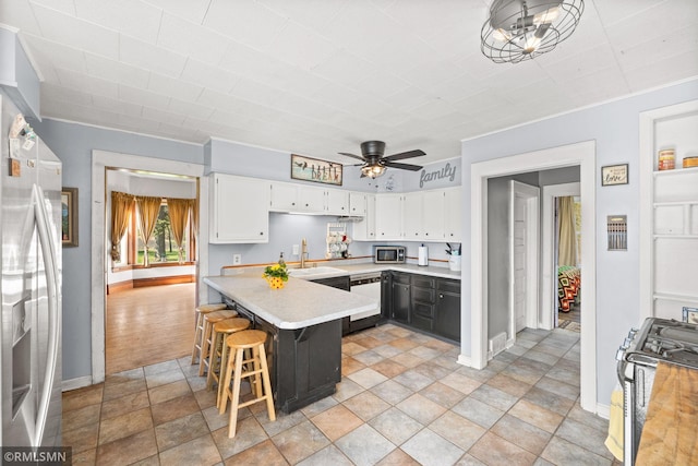 5664 County Road 7 SW, Howard Lake, MN 55349 - kitchen featuring a peninsula, stainless steel appliances, white cabinetry, ceiling fan, and light countertops