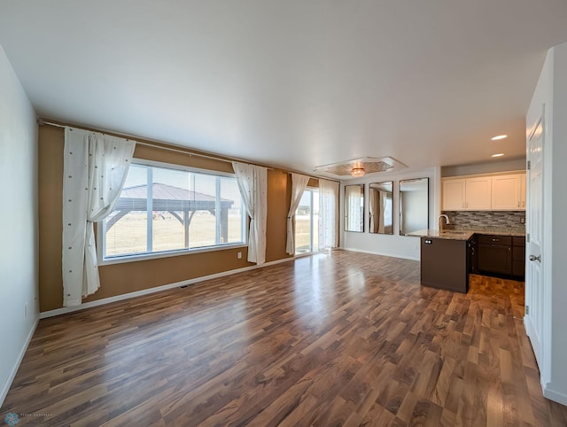 unfurnished living room featuring dark wood-style floors, recessed lighting, baseboards, and a sink