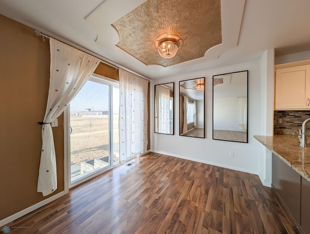 spare room with baseboards and dark wood-style flooring