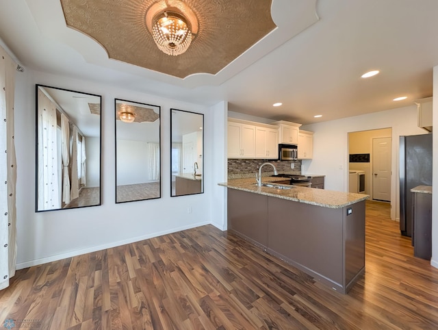 kitchen featuring decorative backsplash, appliances with stainless steel finishes, dark wood-type flooring, and light stone countertops