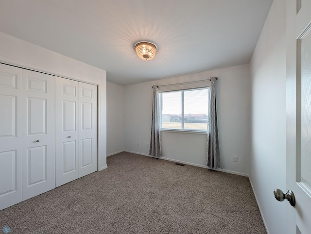 unfurnished bedroom with visible vents, carpet, a closet, and baseboards