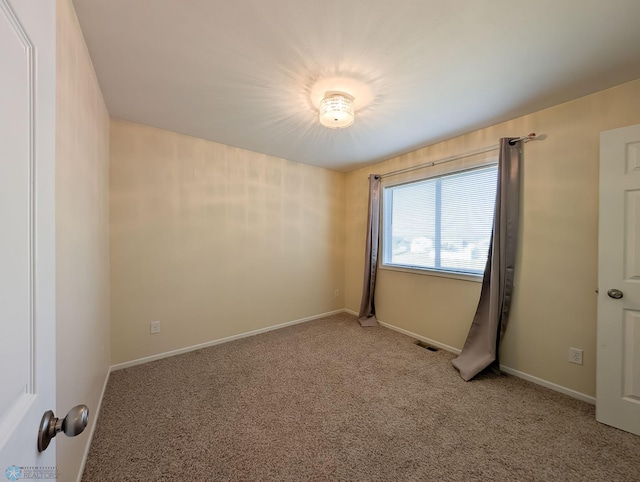 empty room with baseboards, visible vents, and light carpet