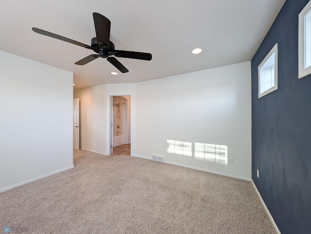 unfurnished room featuring light carpet, visible vents, baseboards, and a ceiling fan