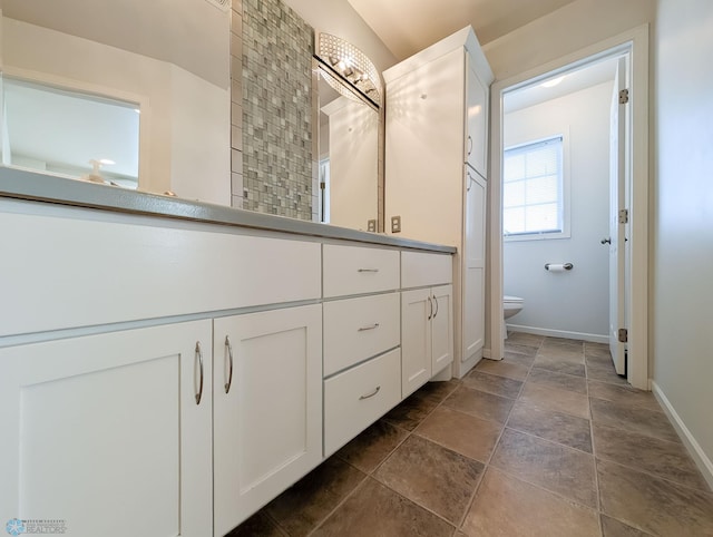 bathroom featuring toilet, vanity, and baseboards