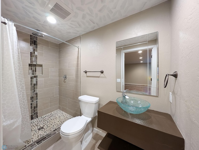 full bathroom featuring toilet, a textured wall, visible vents, and tiled shower