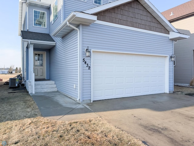 exterior space with central AC, an attached garage, and driveway