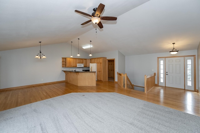 unfurnished living room with baseboards, light wood-style floors, vaulted ceiling, and ceiling fan with notable chandelier