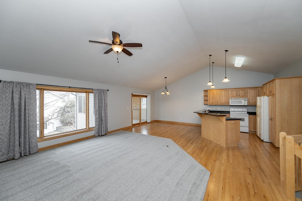 kitchen featuring dark countertops, open floor plan, white appliances, and ceiling fan
