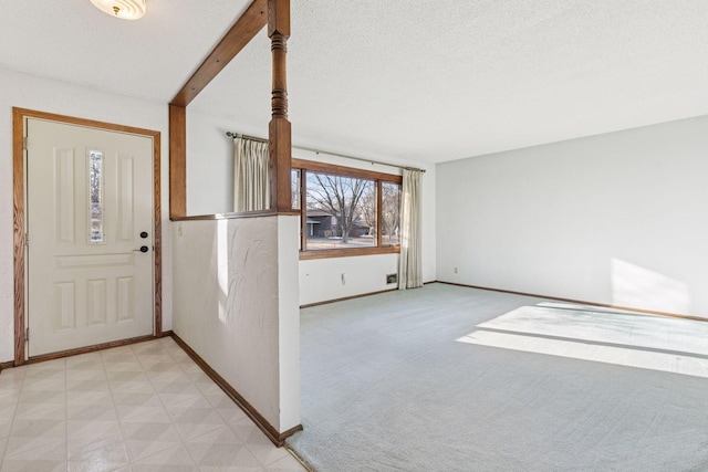 foyer entrance with light colored carpet, a textured ceiling, and baseboards