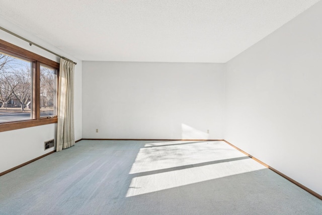 carpeted spare room featuring visible vents, baseboards, and a textured ceiling