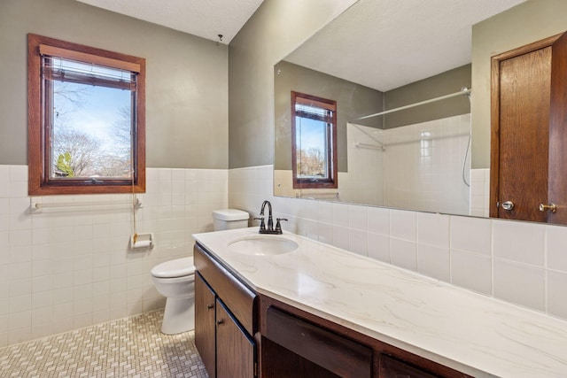 full bathroom with toilet, a textured ceiling, tile walls, a shower, and vanity