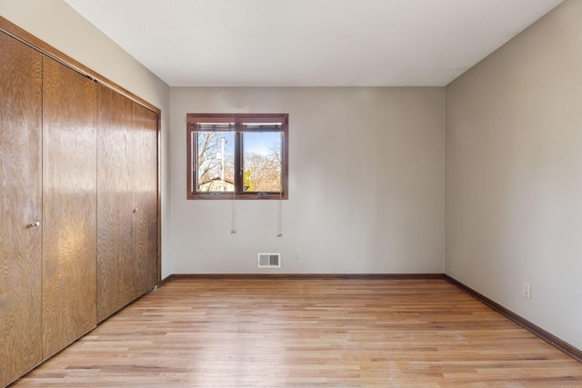 unfurnished bedroom with light wood finished floors, visible vents, baseboards, and a closet