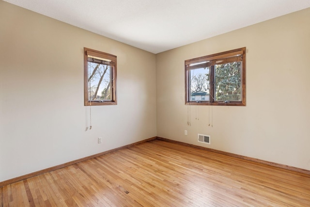 empty room with visible vents, baseboards, a healthy amount of sunlight, and light wood-style flooring