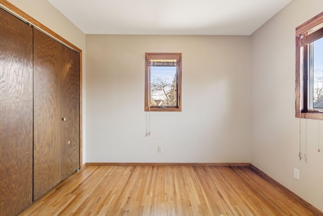 unfurnished bedroom with light wood finished floors, a closet, and baseboards