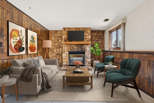 living room with visible vents, wainscoting, wood walls, and a fireplace