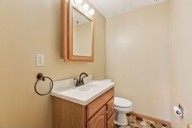 bathroom featuring toilet, vanity, and baseboards