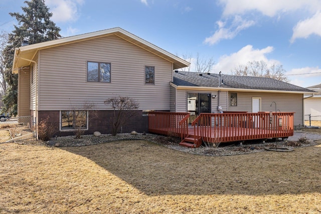 back of house with a wooden deck, a lawn, and fence